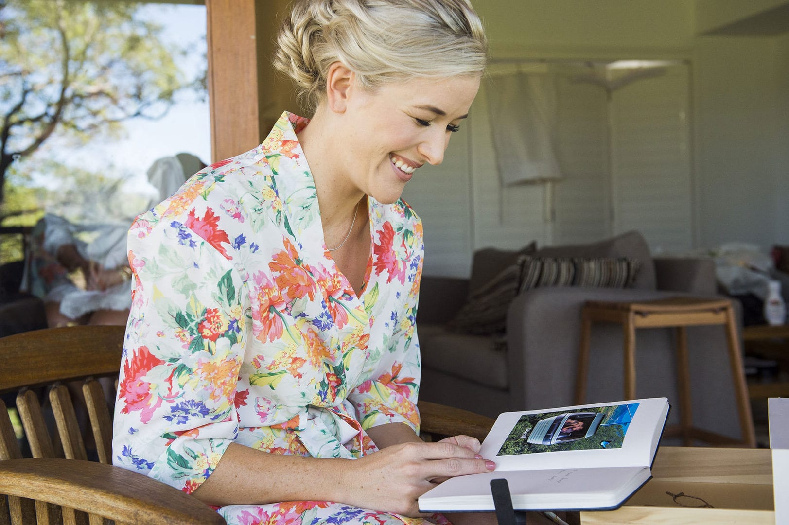 A woman working on a laptop at a cottage table with the deck beyond
