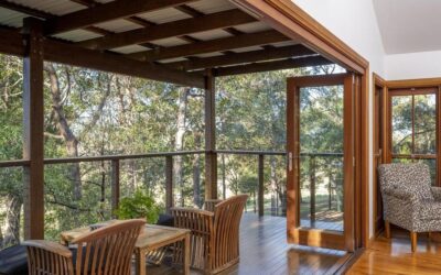 A cottage living space with timber furniture opening onto the deck