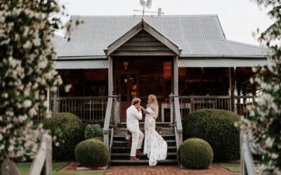 The white timber homestead with a couple on the front steps