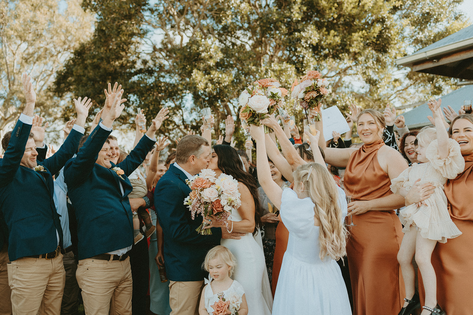 A wedding party cheering on the lawn in late afternoon light