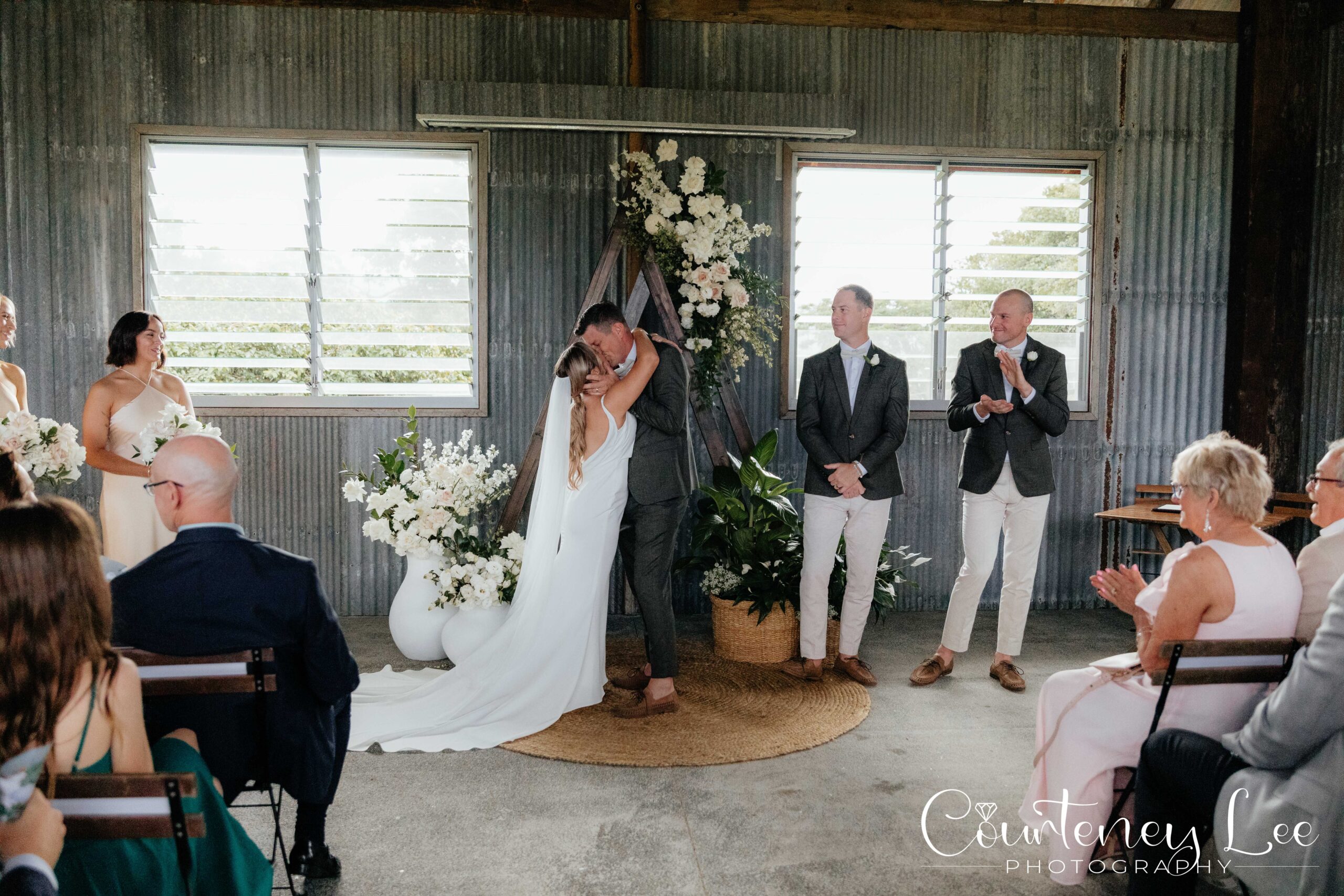 A couple exchanging vows inside the Dairy Barn beneath a floral arch