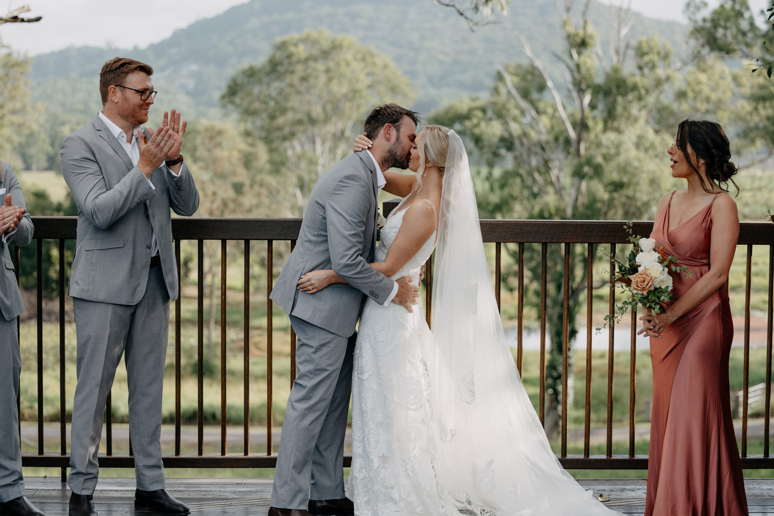 A couple on the timber ceremony deck with guests to either side